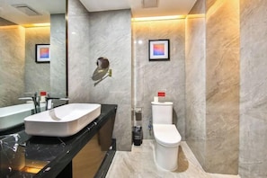 Ein modernes Badezimmer mit schwarzem Waschtisch, einer weißen Spüle, einer Toilette und einem Spiegel.