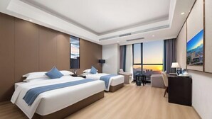 A modern hotel room with two beds, a desk, and a large window offering a city view. - Ramada by Wyndham Zhangjiajie (Zhangjiajie)