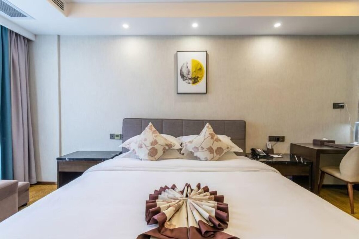 Ein Hotelzimmer mit einem Bett, einem Schreibtisch, einem Sessel, einem Telefon und einem Wandbild.