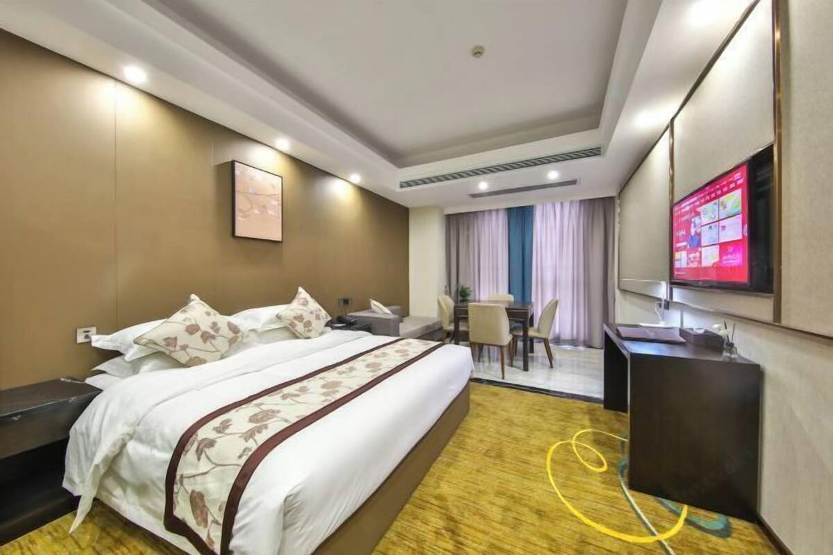 Ein Hotelzimmer mit einem großen Bett, einem Schreibtisch, einem Fernseher und einem Essbereich.