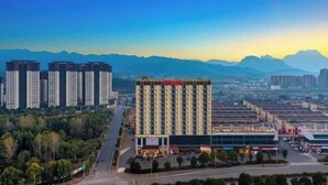 A hotel with a modern design, surrounded by a cityscape and mountains in the background. - Ramada by Wyndham Zhangjiajie (Zhangjiajie)