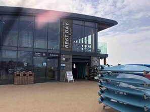 A modern building with a glass facade, labeled "Rest Bay Cafe Bar" and "Entrance."