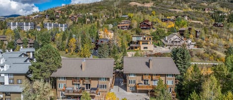 A residential area with modern houses, a swimming pool, and a hilly backdrop.