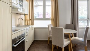 A modern kitchen with white cabinets, a stainless steel sink, and a built-in oven. There is a dining area with a round table and four chairs. - Largo Molina Apartment 1 by Wonderful Italy (Bologna)