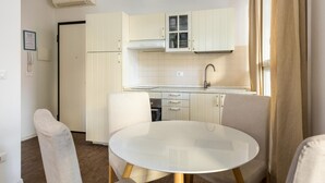 A modern kitchen with white cabinets, a round table, and two chairs. - Largo Molina Apartment 1 by Wonderful Italy (Bologna)