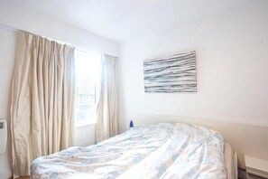 A hotel room with a bed, a window with curtains, and a wall-mounted artwork. - Excellent 2-bed Apartment in Colindale, London (London)
