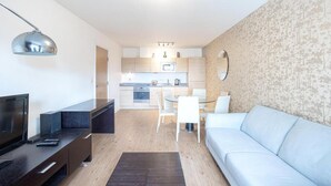 Un salon moderne avec un téléviseur à écran plat, un meuble de rangement en bois foncé et un canapé bleu clair.