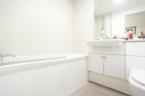 A bathroom with a white bathtub, a sink, and a toilet. - Excellent 2-bed Apartment in Colindale, London (London)