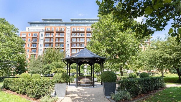 Un kiosque dans un parc, avec un bâtiment en arrière-plan.