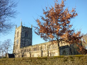 A historic stone building with a clock tower, large windows, and a moss-covered wall.