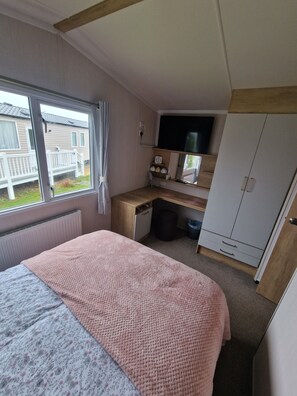 A bedroom with a bed, a desk, a wardrobe, and a window. - 8 Birth Static Caravan (Filey)