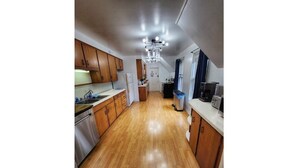 A kitchen with wooden cabinets, stainless steel appliances, and a central light fixture.