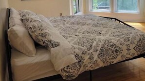 A bedroom with a bed, a window, and a wall-mounted picture of a bull.