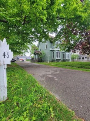 Traditional home on a quiet street with lush green surroundings and a charming front porch.