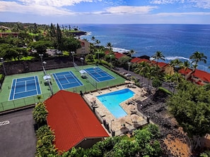 En tennisbana, en swimmingpool och utsikt över havet.