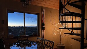 Spiseområde med bord og stole, et vindue med udsigt, et skiudstyrsstativ og en trappe.