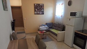Un espace de vie compact comprenant une table à manger, un canapé et une kitchenette.