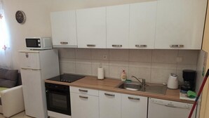 Une cuisine compacte avec des meubles blancs, un four à micro-ondes, une cuisinière et un lave-vaisselle.