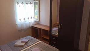 Une chambre à coucher avec un lit, une armoire, un bureau et une fenêtre avec un rideau.