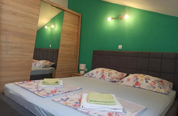 A bedroom with a bed, two nightstands, a mirror, and a green wall.