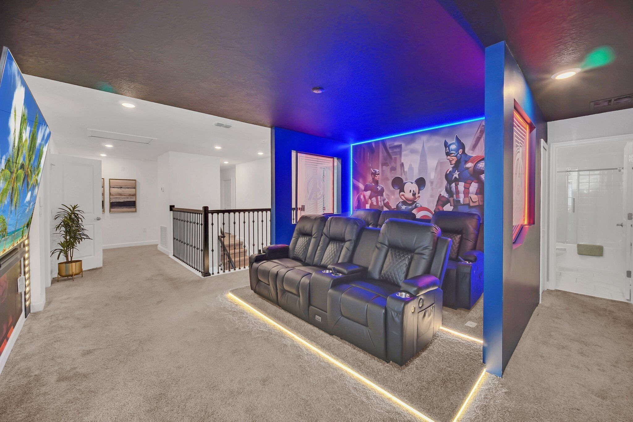 Ein Heimkinozimmer mit einer schwarzen Ledersofa, einer großen Wandmalerei und einer blauen Akzentwand.