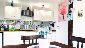 A dining area with a wooden table, a white vase with flowers, and a colorful tile backsplash in the background. - Vesuvio Country House (Campania)