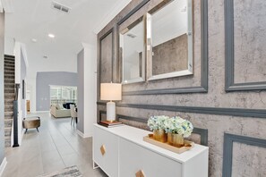 Contemporary living space with a console table, staircase, and glass partition.