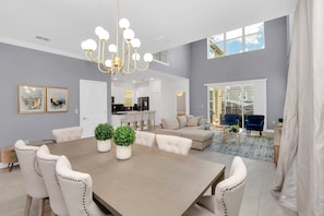Relax in this inviting living area with a large dining table, comfortable sofa, and modern chandelier.