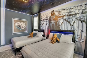 Experience the galaxy in this themed room featuring two beds, a Star Wars mural, and a galaxy ceiling.
