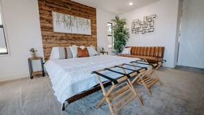 A bedroom with a large bed, wooden headboard, a bench, a plant, and a wall art piece. - Vibey😎Pool House🏡 ModernFarmhouse 1700sqft + View🌄 (Lakeside)