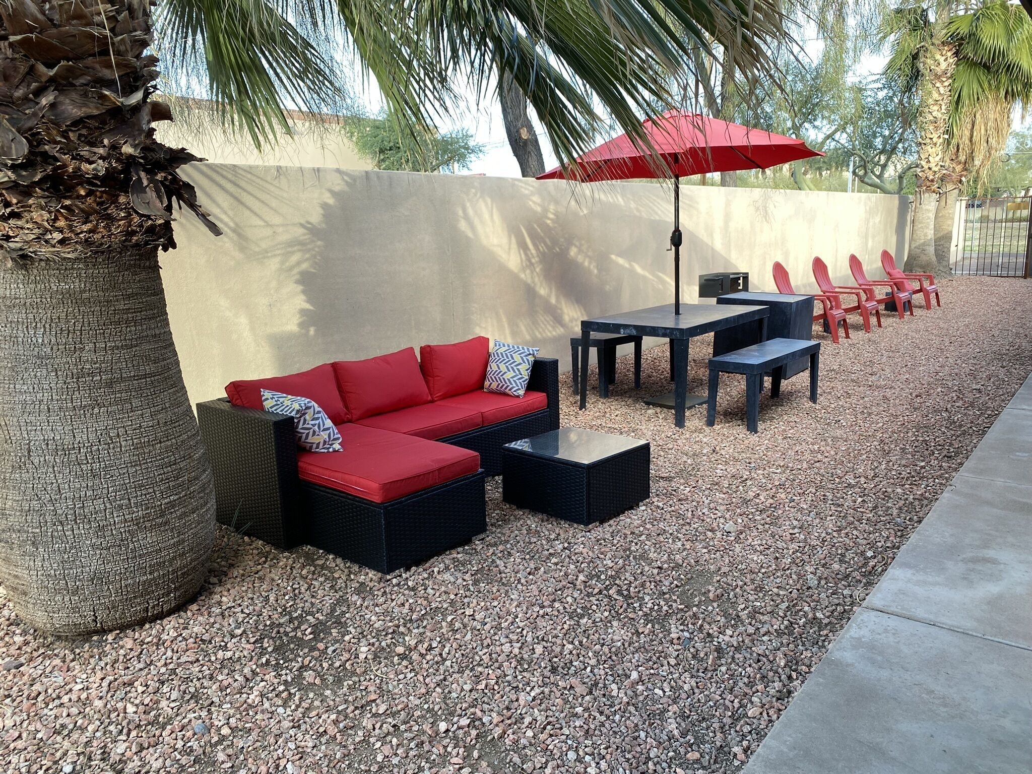 Un espace extérieur aménagé avec un canapé rouge, des tables noires et des chaises rouges.