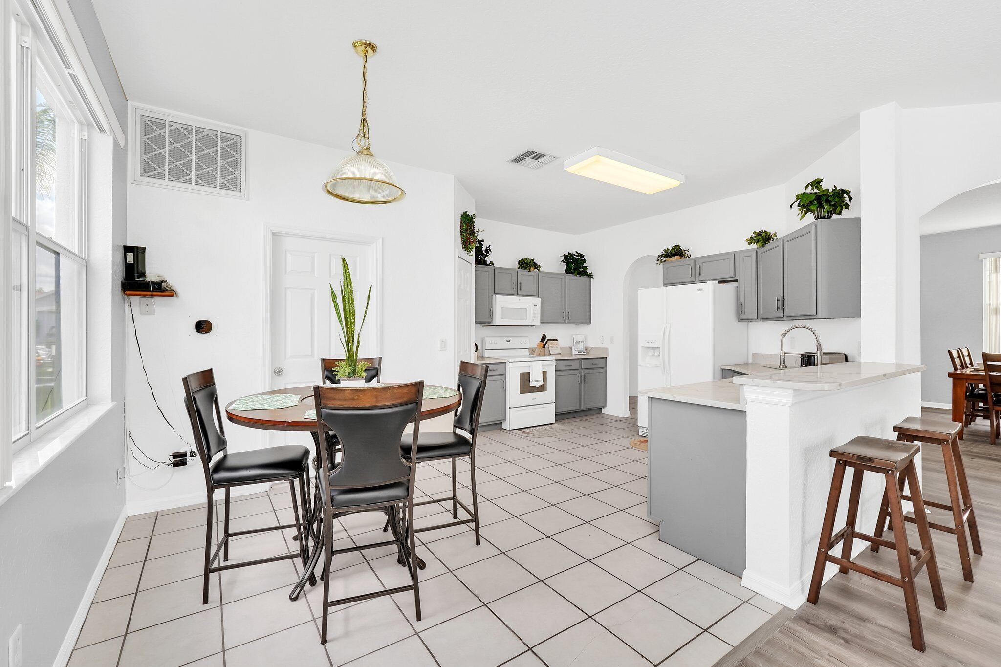 A modern kitchen with white cabinets, a central island, and a dining area with chairs.