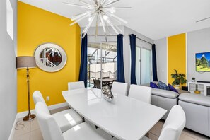 Relax in this stylish living room with a central dining table, comfortable sofa, and large mirror.