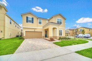 A two-story residential building with a garage, a paved driveway, and a well-maintained lawn.