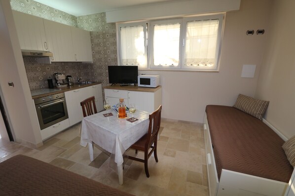 A compact kitchen with a dining table, a microwave, and a television. - The WHITE Room at Villa dei Colori, in the hills of Monopoli (Gorgofreddo)