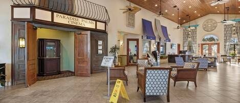 A cinema with a sign reading 'Paradise Palms Cinema' and a reception area with seating and a sign that says 'Welcome to Paradise Palms.'