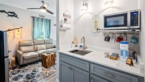 Un espacio habitable compacto con kitchenette, que incluye microondas, cafetera y lavamanos.