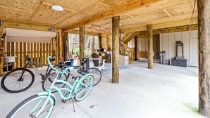 Un espacio al aire libre cubierto con vigas de madera, bicicletas y suelo de concreto.