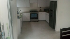 A compact kitchen with white cabinets, a built-in oven, a microwave, and a refrigerator. - Casa Coral 25, private, safe and in a privileged location... (Ensenada)