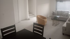 A modern living room with a sofa, a coffee table, and a chair. There is a staircase leading to another level. - Casa Coral 25, private, safe and in a privileged location... (Ensenada)