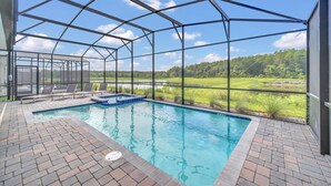 A covered outdoor swimming pool with a view of a green landscape. - Beautiful Lake View Villa with Game Room-2989PS (Kissimmee)