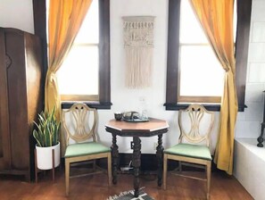 Relax in this cozy corner room with a wooden table, two chairs, and a potted plant.