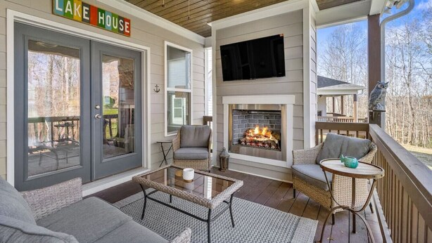 A covered porch with a fireplace, outdoor seating, and a sign reading 'LAKE HOUSE'. - Hope's Crest · Beautiful Home with Lake/Marina Access and Firepit (Tullahoma)
