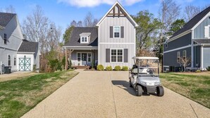A two-story house with a driveway, a golf cart, and a garage. - Hope's Crest · Beautiful Home with Lake/Marina Access and Firepit (Tullahoma)