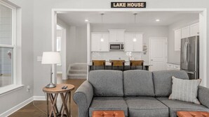 A modern living room with a gray sofa, wooden coffee table, and a sign reading 'LAKE HOUSE'. - Hope's Crest · Beautiful Home with Lake/Marina Access and Firepit (Tullahoma)