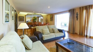 A spacious living room with a sofa, a coffee table, and a dining area in the background.