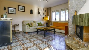 A living room with a sofa, a coffee table, a fireplace, and a tiled floor.