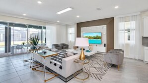 Un salon moderne comprenant un canapé, un téléviseur et un coin repas avec une table et des chaises.