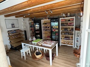En butik med træbjælker, hylder fyldt med forskellige produkter og et bord med kurve.