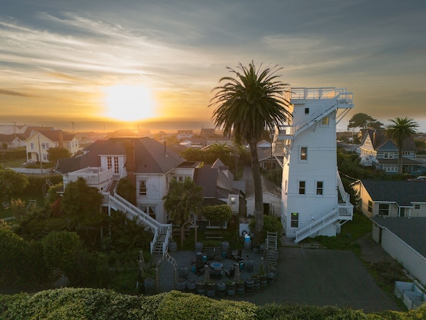 A residential area with houses, a prominent white building with a staircase, and a palm tree.